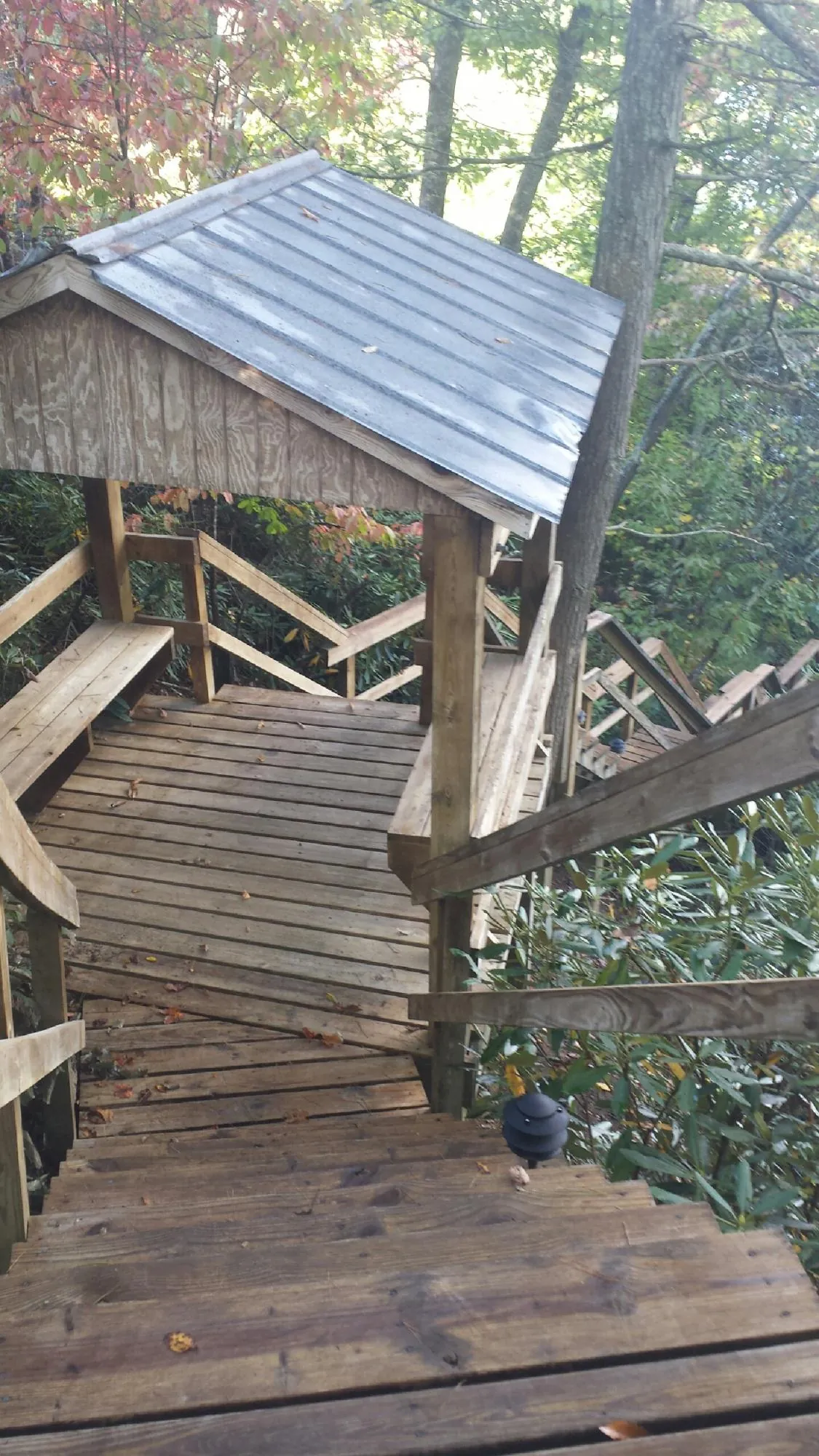 Metal roofed shelter over wooden steps on a wooded walkway — Skylight Repair & Installation work by our crew in Ogden